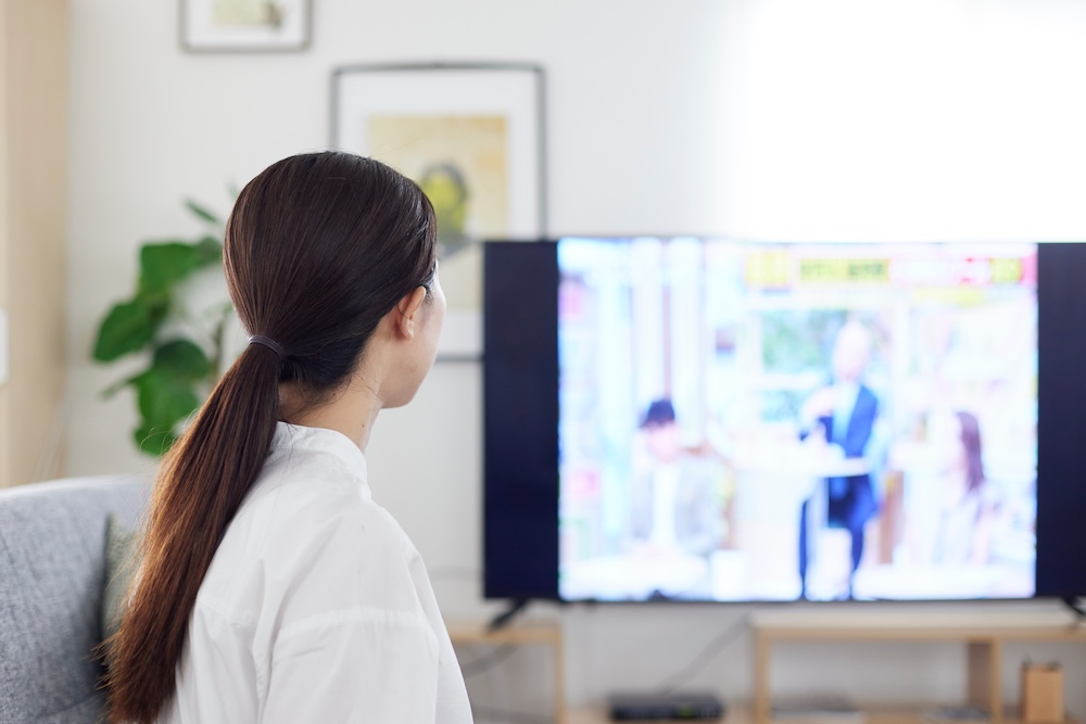 リビングにてテレビを見る日本人の女性の後ろ姿